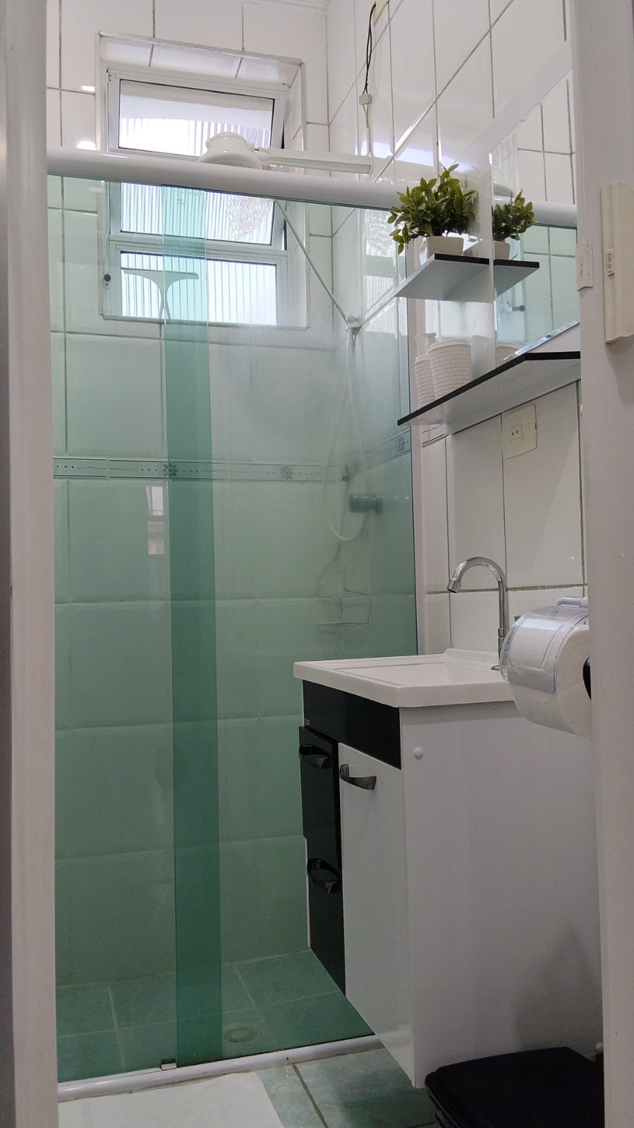 Banheiro privativo com box de vidro e acabamento limpo